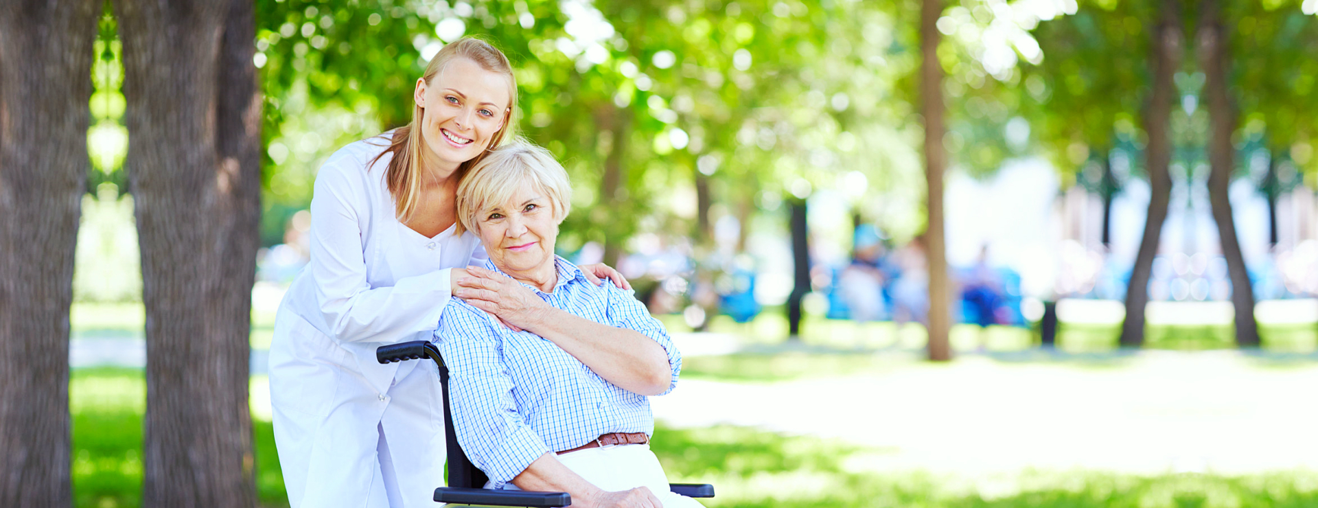 caregiver and elderly woman in a wheelchair smiling